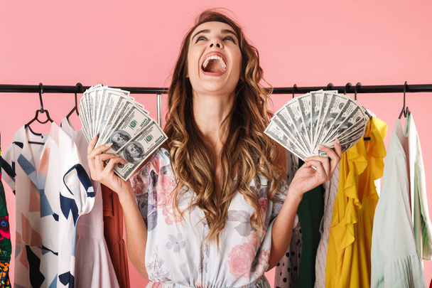 Obrázek vzrušená dívka stojící poblíž šatník zatímco drží peníze - Fotografie, Obrázek