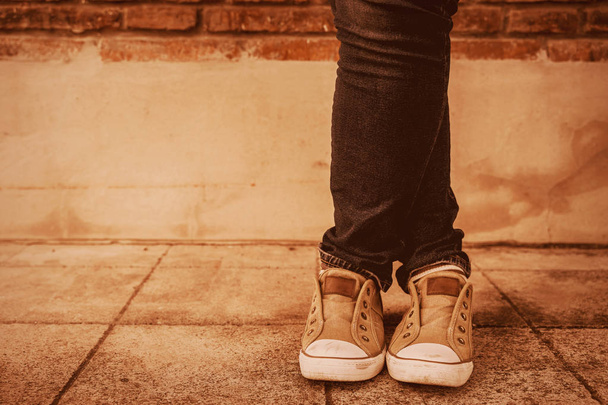 Shapely female cross one's legs  in sneakers and jeans near a co - Photo, Image