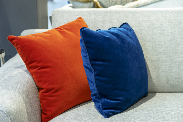 Oreillers décoratifs orange et bleu sur un canapé beige
. - Photo, image
