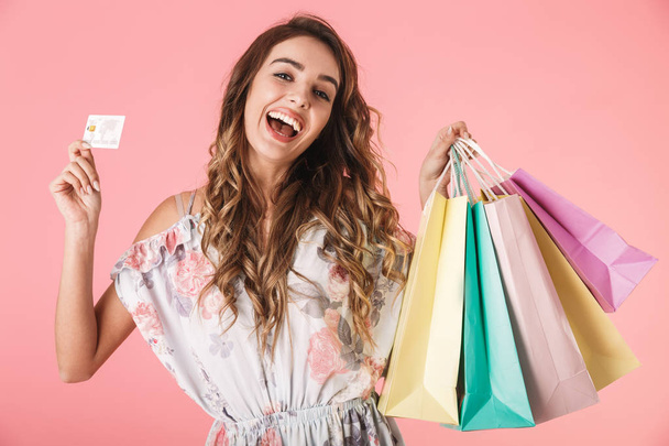 Obrázek radostné ženy 20s v šatech drží kreditní kartu a barvy - Fotografie, Obrázek