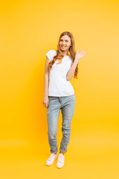 Full length, positive girl, shows a greeting gesture, on a yello - Foto, immagini