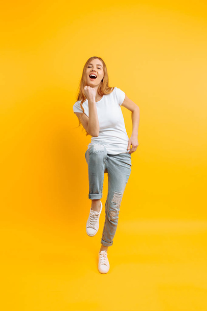 Full length, enthusiastic girl , celebrating success on a yellow - Foto, afbeelding