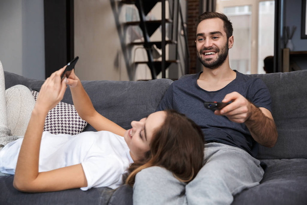 Cheerful young couple relaxing on couch at home - Fotoğraf, Görsel