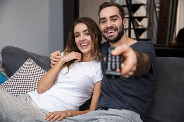 Cheerful young couple relaxing on couch at home - Фото, зображення