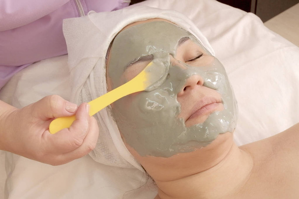 Kosmetyczka stosuje alginian maski z alg na oczach dziewczyny. Zabieg odmładzający w salonie piękności. Kosmetyka do pielęgnacji twarzy i ciała - Zdjęcie, obraz