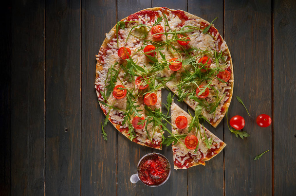 Italian pizza with tomatoes, cheese and herbs on vintage wooden background. Top view - Foto, imagen
