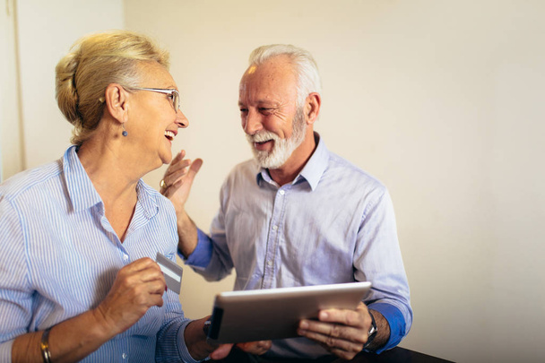 Modernes Senioren-Paar kauft online mit Tablet und Kreditkarte ein - Foto, Bild