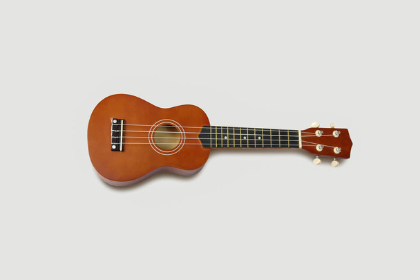 Izolované na měkké šedé pozadí hnědé ukulele kytara. - Fotografie, Obrázek