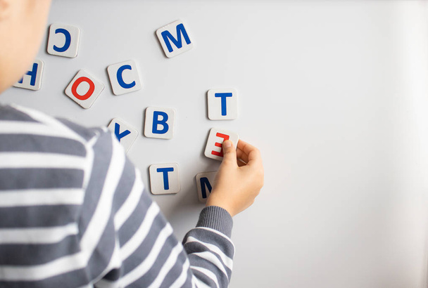 Ребенок учит буквы на доске. Мальчик изучает буквы.
. - Фото, изображение