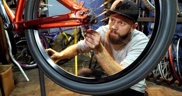 A young mahanic fixing a bicycle wheel in her repair workshop - Фото, изображение
