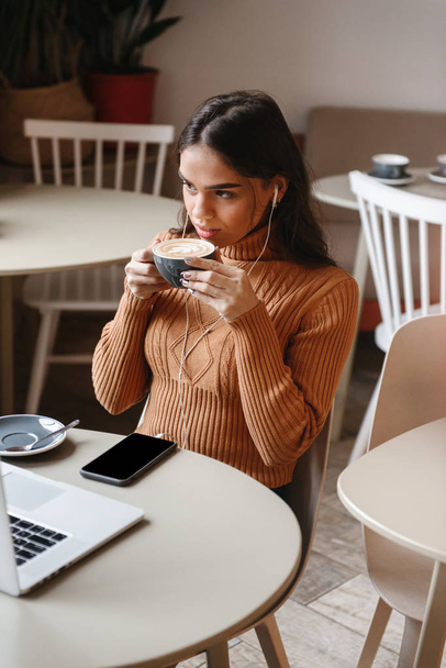 Pretty beautiful woman sitting in cafe indoors using laptop computer. - Photo, Image