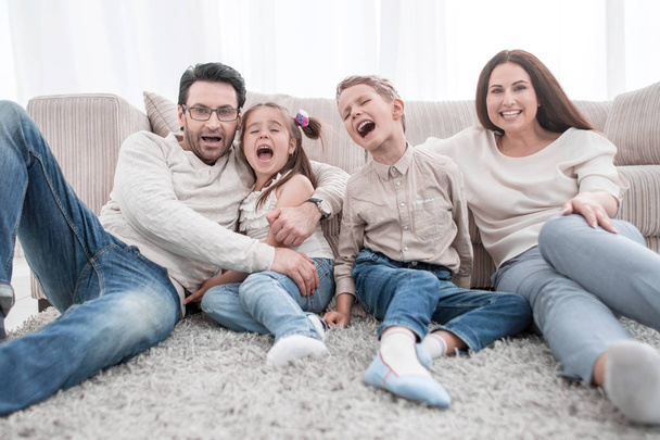 happy family sitting on the carpet in the living room - Φωτογραφία, εικόνα
