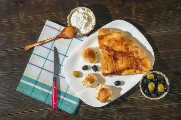 Bureks με τυρί - εθνικό πιάτο, δημοφιλή στα Βαλκάνια. Kajmak σε μικρό πιάτο. Επίπεδη θέσει. Σκούρο φόντο για ρουστίκ - Φωτογραφία, εικόνα