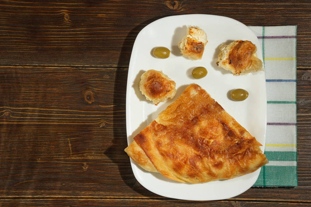 Balkanin ruokia. Burek juustolla, suosittu kansallinen ruokalaji. Litteä pano. Tumma maalaistausta. Vapaa tila tekstille
 - Valokuva, kuva