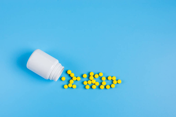 Желтые таблетки, таблетки и белая бутылка на синем фоне
.  - Фото, изображение