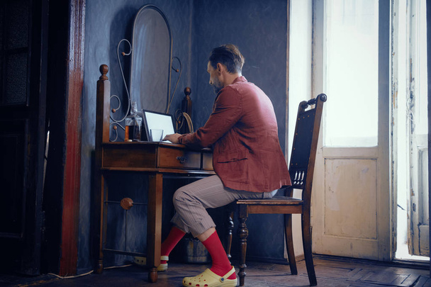 Stylish Man of Brutal Appearance at Home at a Desk Working on a Laptop. - Foto, afbeelding
