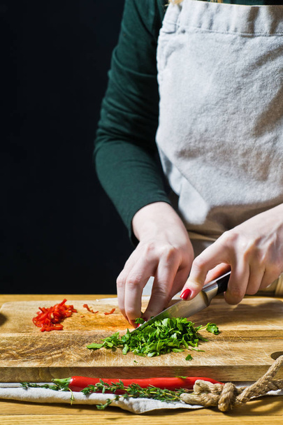 Hände Koch schneiden Koriander. schwarzer Hintergrund, Seitenansicht, Küche, s - Foto, Bild