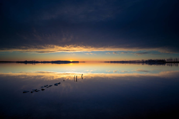 Atmosférické západ slunce nad zrcadlení vodní hladiny s threatenin - Fotografie, Obrázek