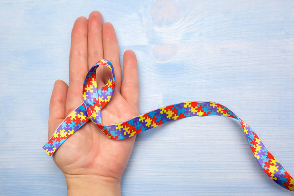 World Autism awareness and pride day with Puzzle pattern ribbon on hand - Valokuva, kuva