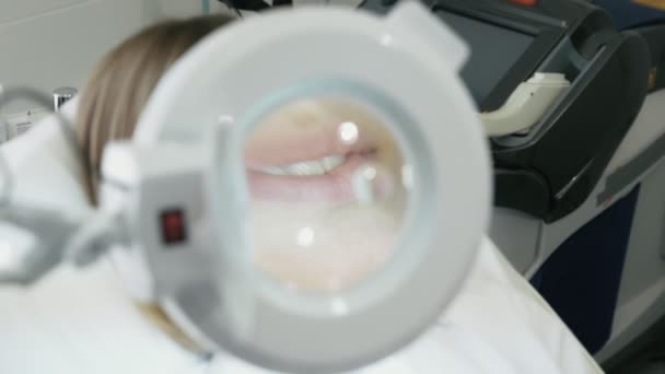 Bliska uśmiechający się kobiece usta przez szkło kosmetyczne Lupa - Materiał filmowy, wideo