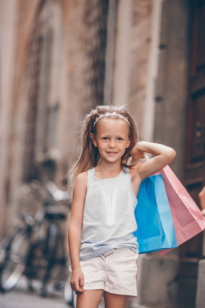 Retrato de niña adorable caminando con bolsas de compras al aire libre en la ciudad europea
. - Foto, imagen