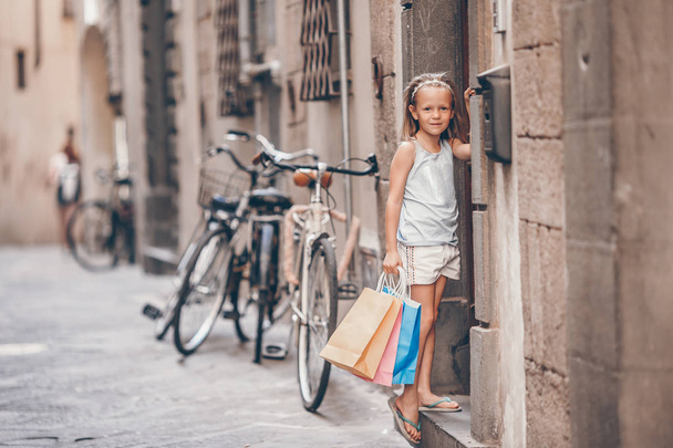 Portrait of adorable little girl walking with shopping bags outdoors in european city. - 写真・画像