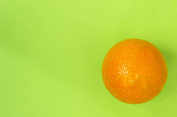 Isolated orange orange against a green background - Фото, изображение