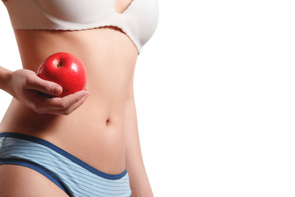 close up. slender slim figure waist belly young woman girl. Holding a juicy red Apple. isolated on white background - Zdjęcie, obraz