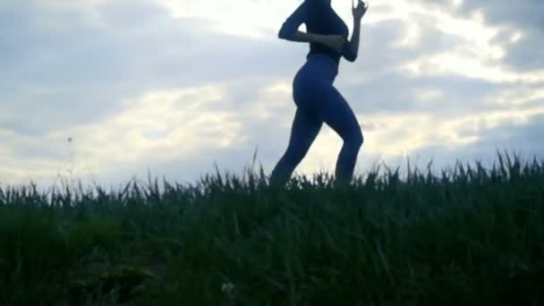 Lassított lejátszás Close Up, női futás-on sunrise silhouette háttér. Lány jogging oldalnézet, követés lövés közelről arany napkeltekor - Felvétel, videó