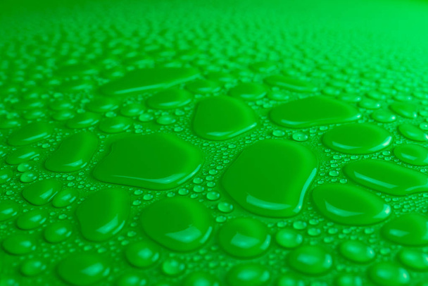 Droplets of water on a green, matte background illuminated with a delicate light. - Photo, Image