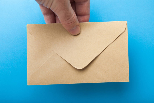 Poštovní obálky z recyklovaného papíru v ruce na modrém pozadí - Fotografie, Obrázek