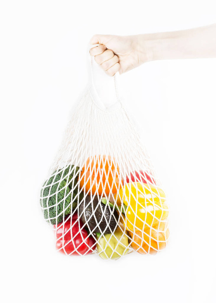 Woman hand holding a shopping bag with vegetables, fruits on a white background - Фото, изображение