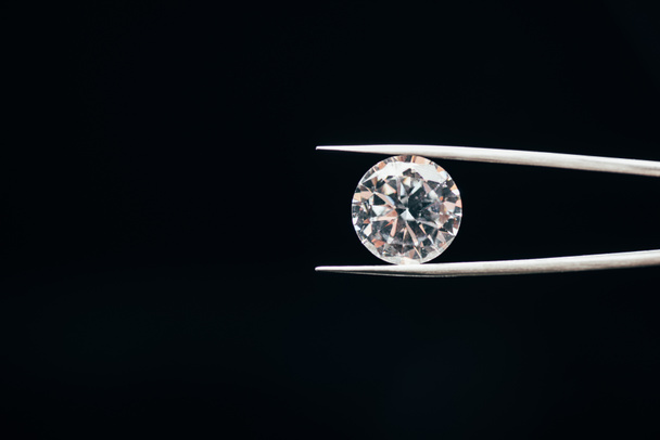 diamant brillant pur transparent dans des pinces isolées sur noir
 - Photo, image