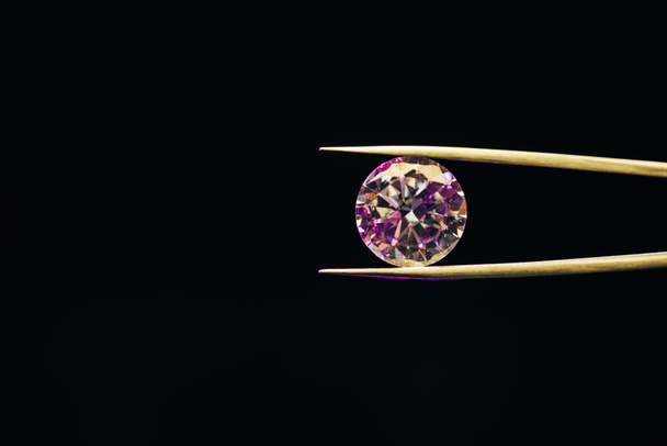 colorful pure sparkling diamond in tweezers isolated on black - Photo, Image