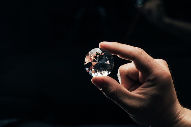részleges kilátás nyílik ember tartja nagy tiszta csillogó gyémánt fekete háttér - Fotó, kép