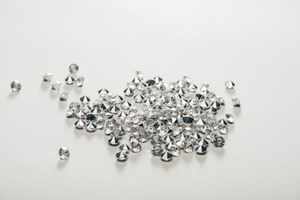 прозрачные чистые бриллианты, разбросанные на белом фоне
 - Фото, изображение