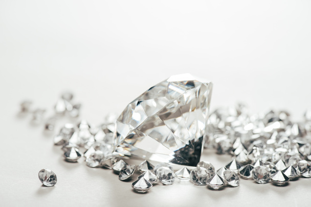 selektiver Fokus der funkelnden reinen großen Diamanten unter kleinen auf weißem Hintergrund - Foto, Bild