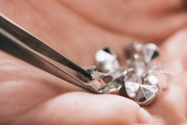 close up of tweezers near shiny diamonds in hand - Photo, Image