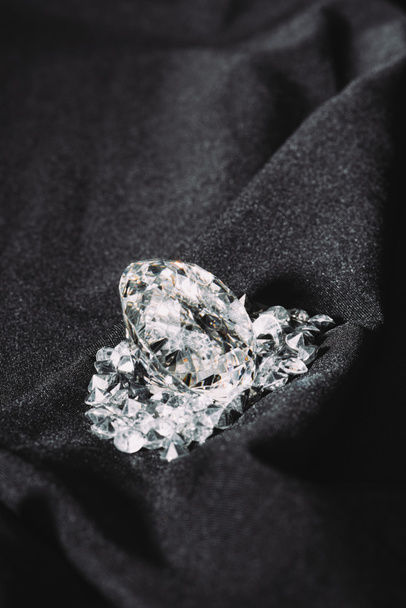 pile de diamants purs brillants sur tissu texturé noir
  - Photo, image