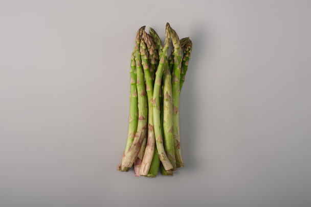 top view of green organic raw asparagus in pile on grey background - Foto, Bild