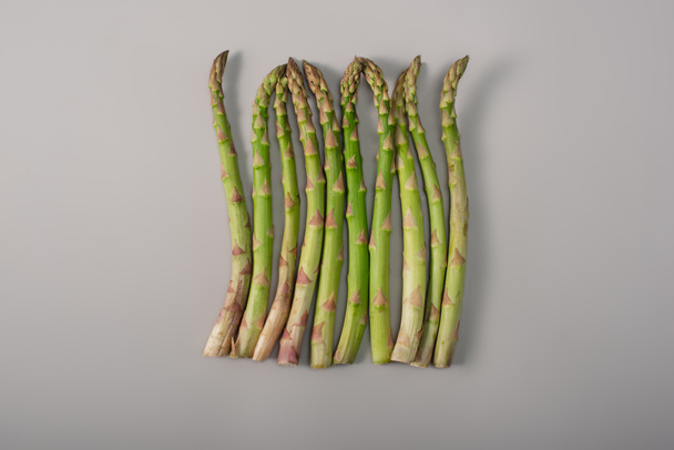 top view of green organic raw asparagus in row on grey background - Photo, Image