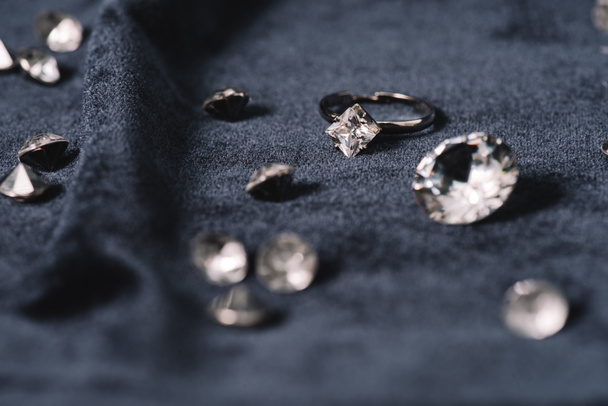 επιλεκτική εστίαση δαχτυλίδι αρραβώνων κοντά λαμπερά διαμάντια σε μπλε ύφασμα - Φωτογραφία, εικόνα