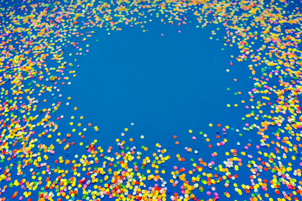 Confetti colorido en frente de fondo azul
.  - Foto, Imagen