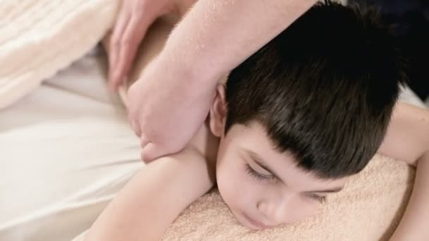 Primer plano masajista fisioterapeuta masculino hace un masaje relajante curativo a un niño pequeño acostado en una cama de masaje. Masaje de espalda
 - Metraje, vídeo