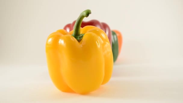 Gelbe, rote, grüne und orangefarbene Paprika gegen weiße - Linienanordnung - Dolly links - Filmmaterial, Video