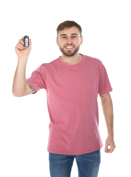 Happy young man with car key on white background. Getting driving license - Фото, изображение