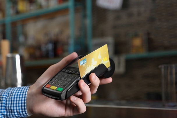 Homem usando máquina de cartão de crédito para não pagamento em dinheiro no café, close-up. Espaço para texto
 - Foto, Imagem
