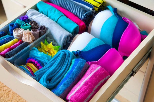 Neatly folded clothes with accessories in chest of drawers - Zdjęcie, obraz
