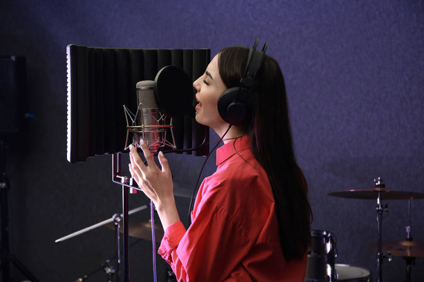 Young singer with microphone recording song in studio - Foto, Imagem