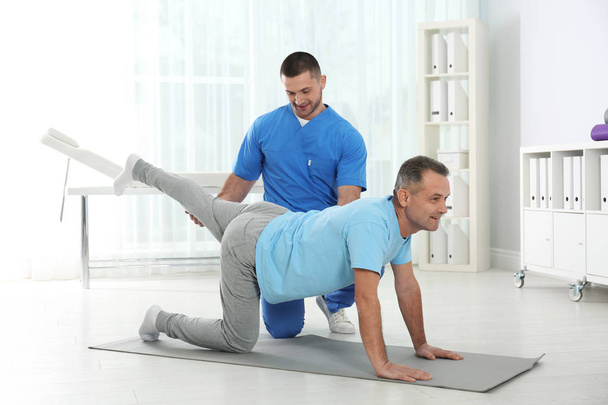 Doctor working with patient in hospital. Rehabilitation exercises - Foto, afbeelding